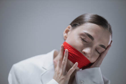 Stressed woman whose mouth is gagged shut.